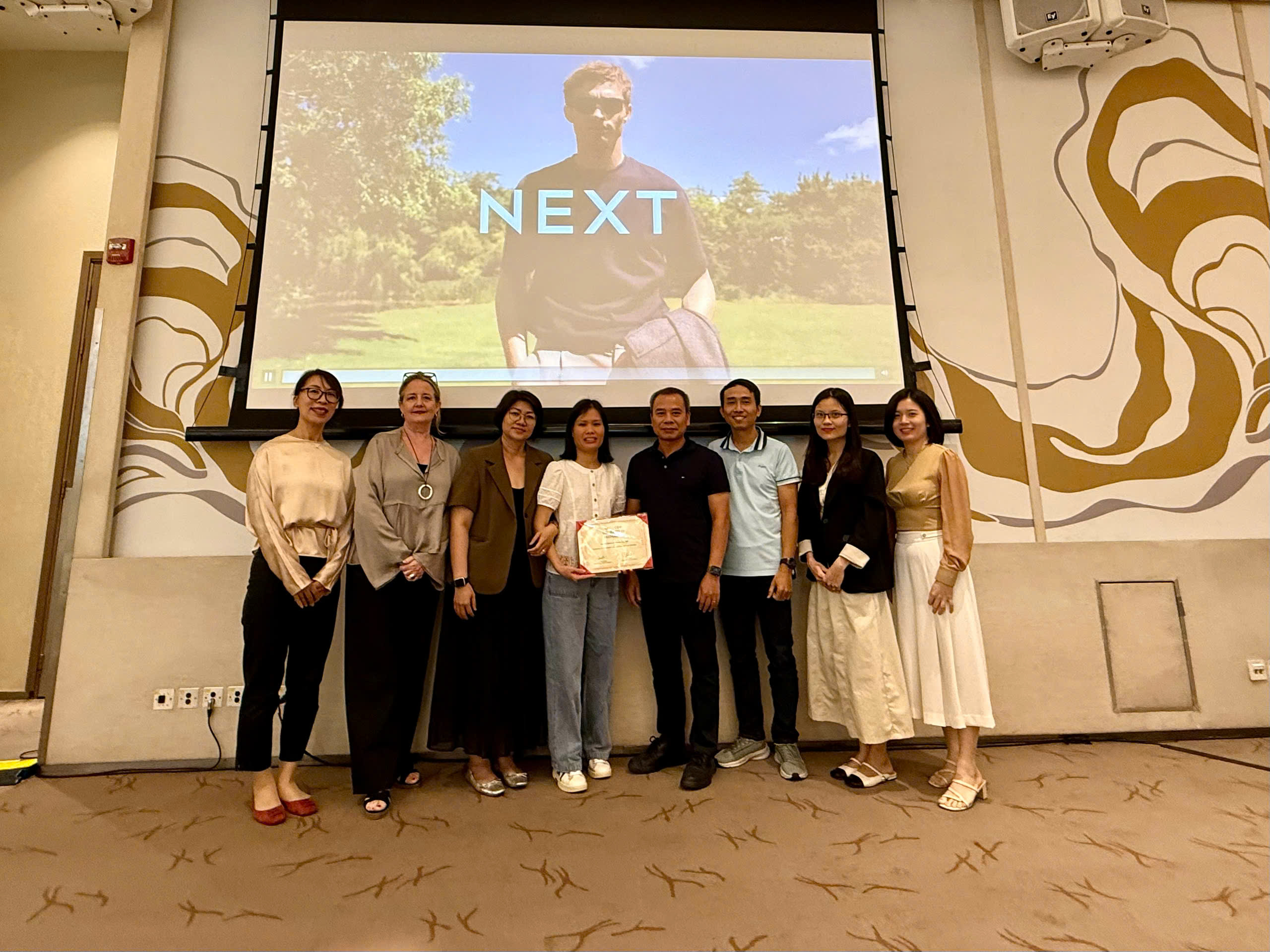 A representative of Hatay Shoes receives a certificate of recognition from NEXT